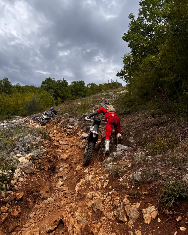 Braucējs ar motociklu kāpj pa akmeņainu enduro taku