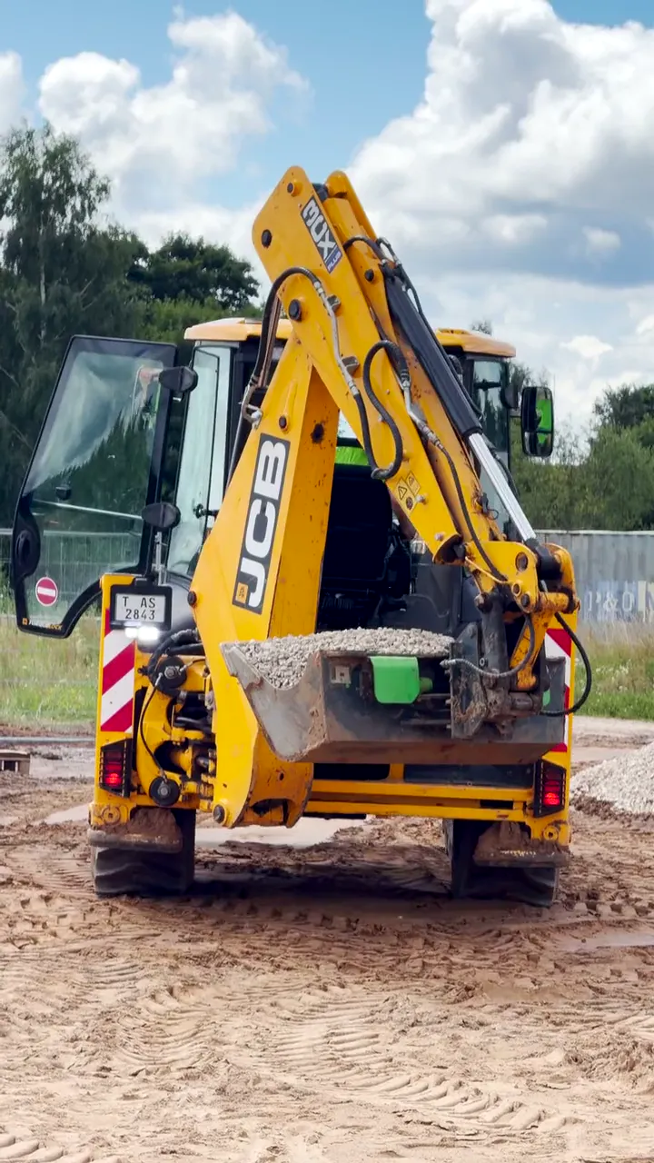 A yellow excavator on a construction site where we film the assembly of a house
